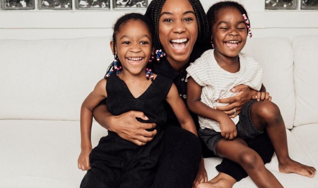 a woman sitting on a couch with two kids