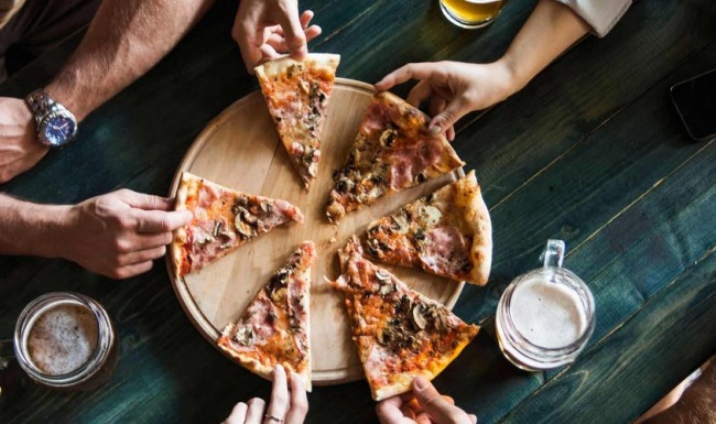 a group of people eating pizza